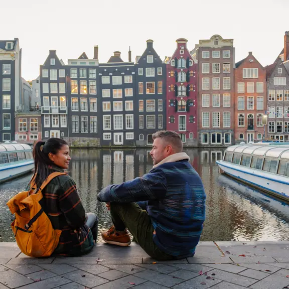 Een vrouw en een man die samen zitten bij de grachten in Amsterdam