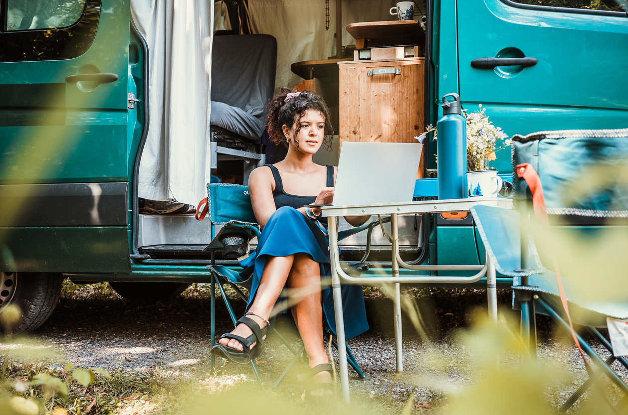 A digital nomad working on her laptop while camping