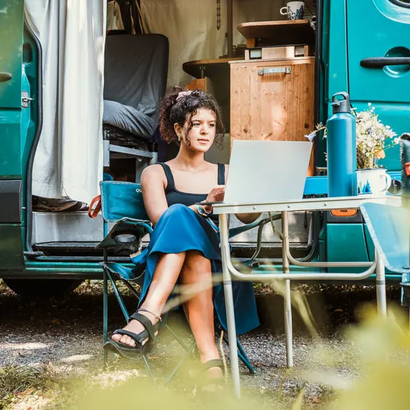 A digital nomad working on her laptop while camping